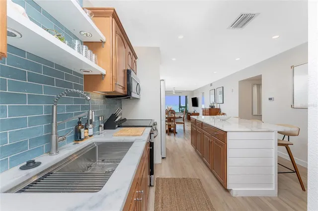 a kitchen with stainless steel appliances granite countertop a sink a stove and a wooden floors