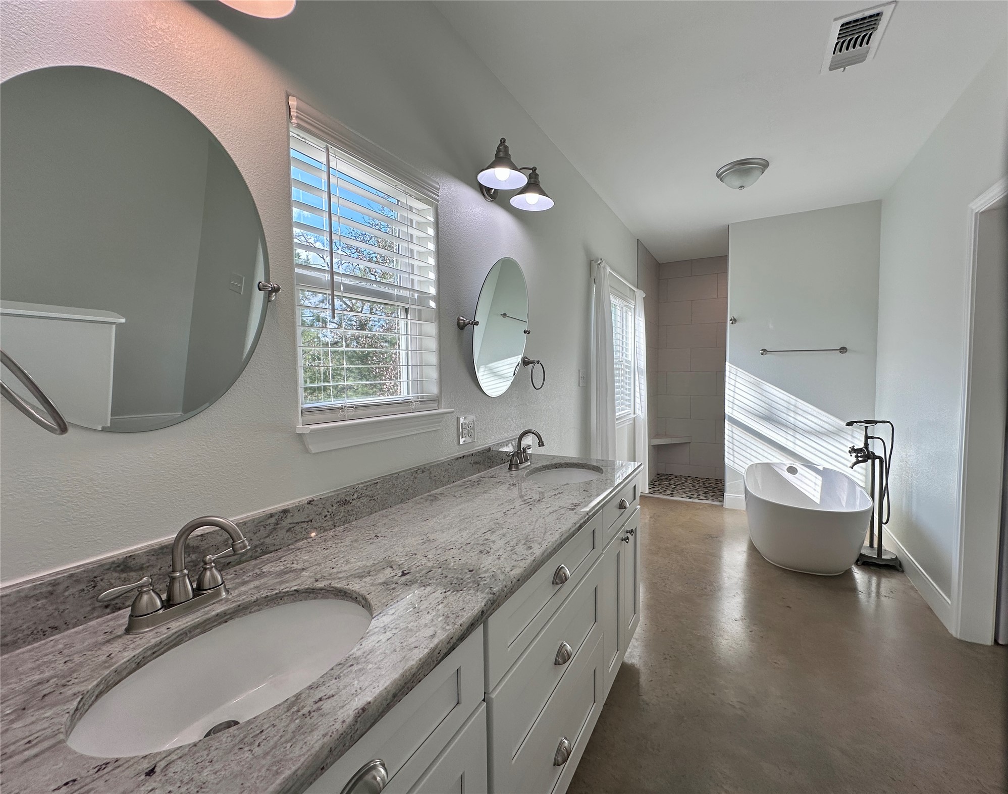 124 Pine Path Bastrop, TX 78602 - Photo 14 of 31 Bathroom with concrete floors, a soaking tub, double sinks, and windows