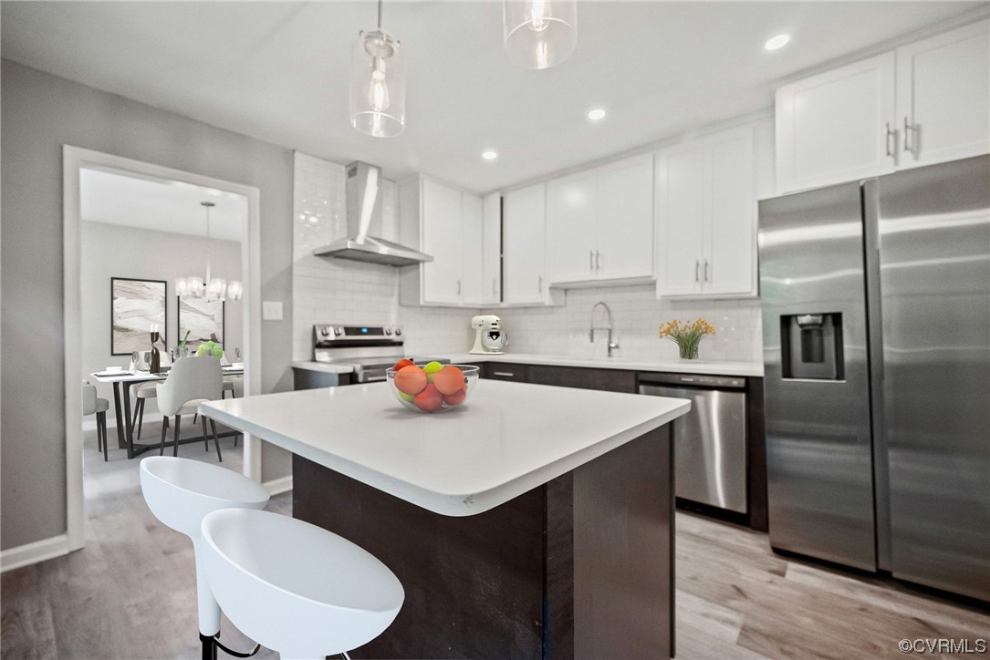 a kitchen with stainless steel appliances granite countertop a sink a stove a refrigerator and white cabinets