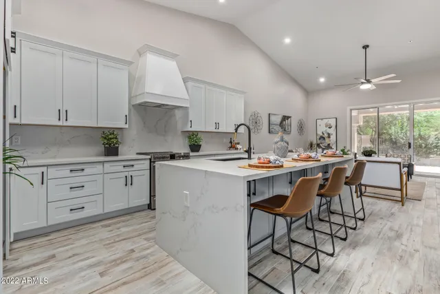 a kitchen with stainless steel appliances white cabinets a stove a sink and a potted plant