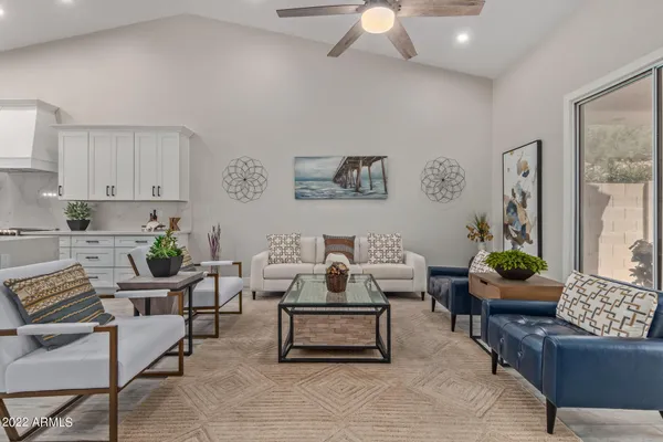 a living room with furniture kitchen view and a wooden floor