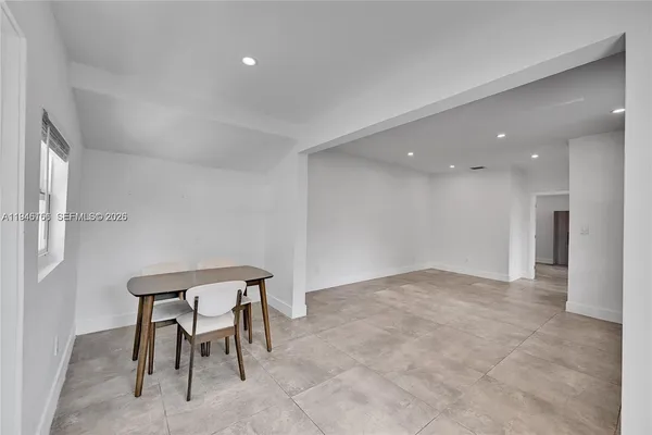 a view of an empty room and kitchen with a sink
