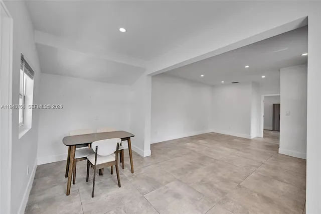 a view of an empty room and kitchen with a sink