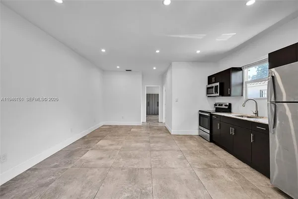 a large white kitchen with a refrigerator a stove top oven a sink and dishwasher