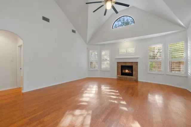 an empty room with windows fireplace and fans