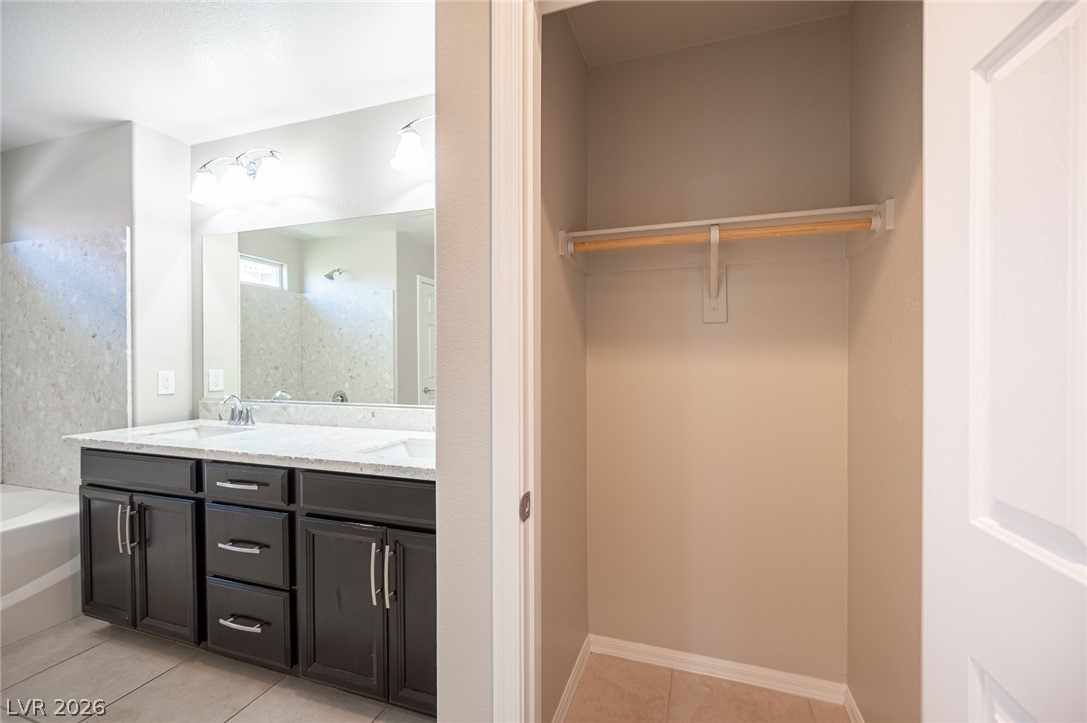 9916 Sable Point Street Las Vegas, NV 89178 - Photo 50 of 73 Double vanity with ample storage accompanies a convenient walk-in closet, ready for personalized organization.