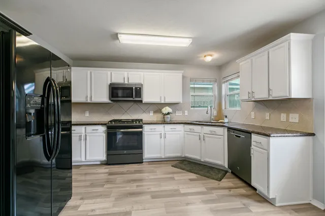 a kitchen with granite countertop a stove top oven and refrigerator