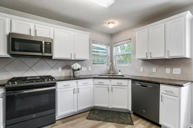 a kitchen with cabinets appliances a sink and a window