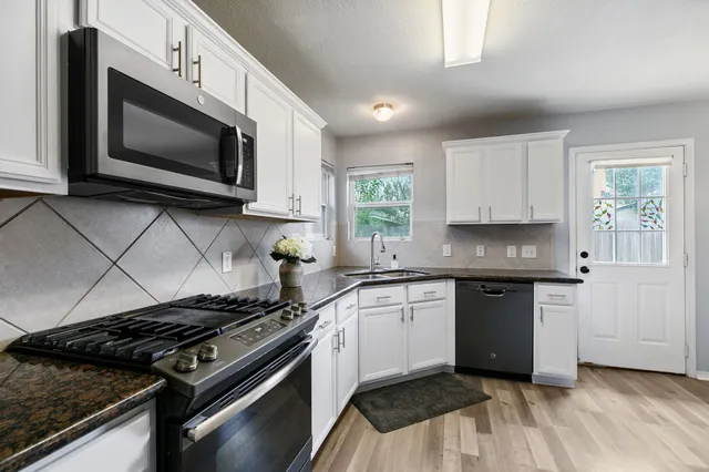 a kitchen with stainless steel appliances granite countertop a stove a microwave and a sink