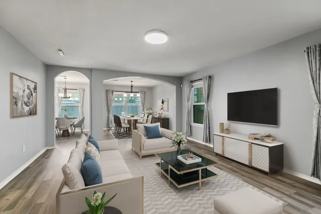 a living room with furniture a flat screen tv and a large window