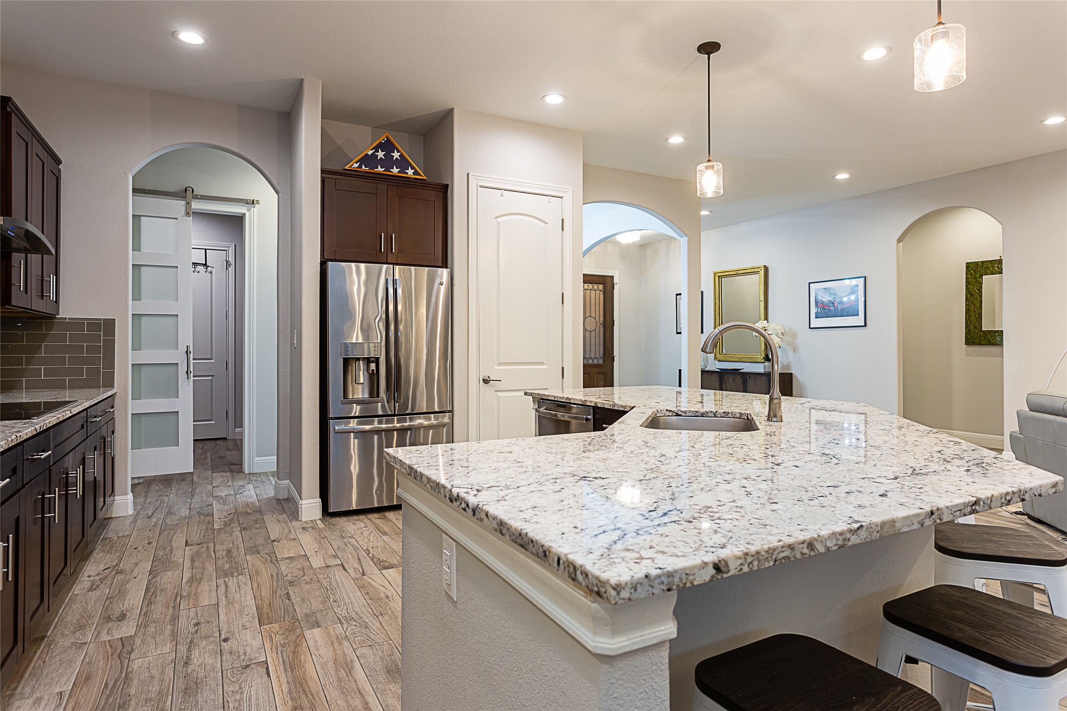 5608 Arroyo Road Austin, TX 78734 - Photo 16 of 39 Kitchen featuring stainless steel appliances, light stone countertops, a barn door, dark brown cabinets, and decorative light fixtures
