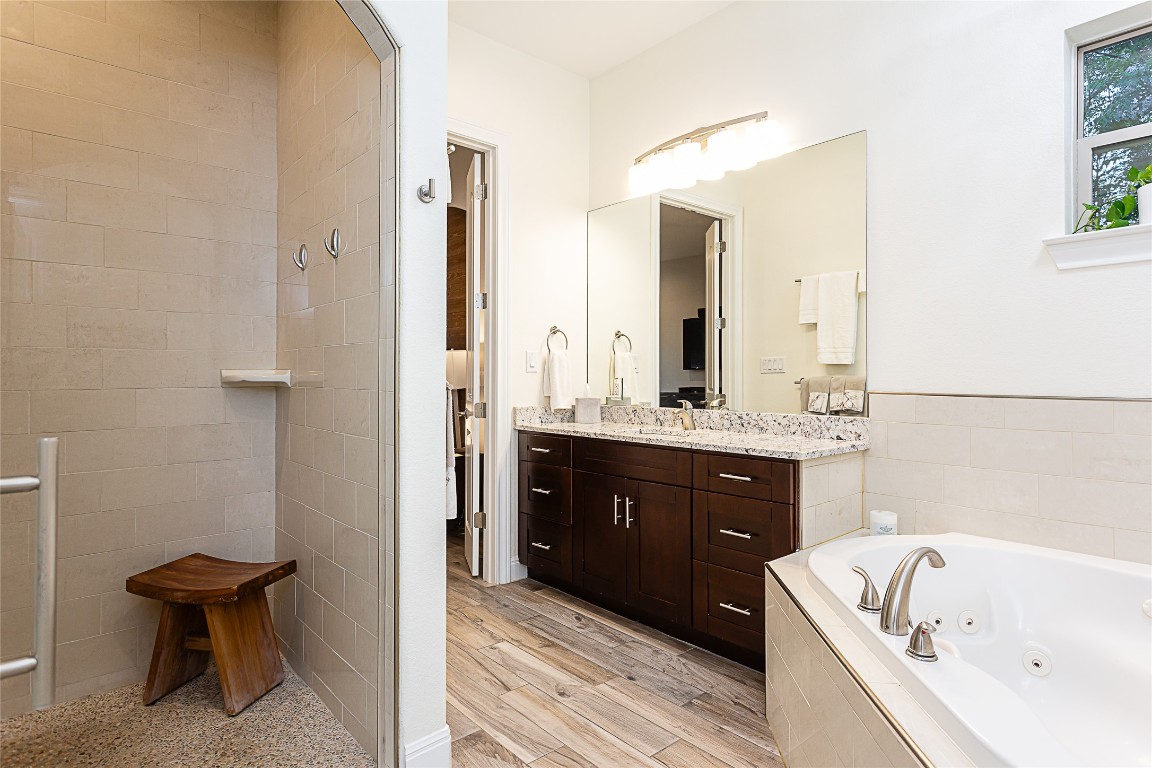 5608 Arroyo Road Austin, TX 78734 - Photo 24 of 39 Full bath with vanity, a whirlpool tub, light wood finished floors, and walk in shower