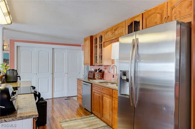 a kitchen with stainless steel appliances granite countertop a refrigerator a stove and a sink with wooden floor