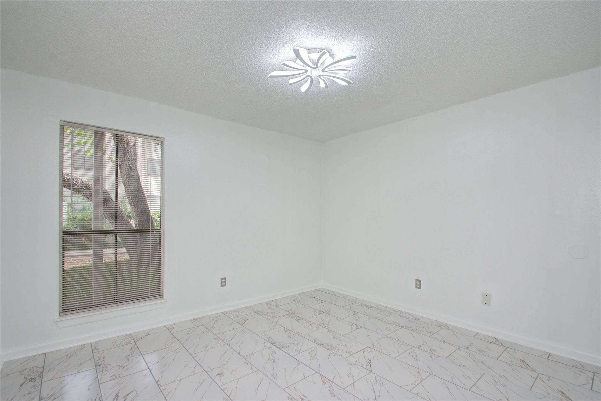 17331 Red Oak Drive, Unit 45 Houston, TX 77090 - Photo 18 of 25 an empty room with chandelier fan and windows