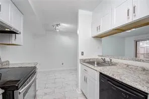 a kitchen with granite countertop a sink stove and cabinets