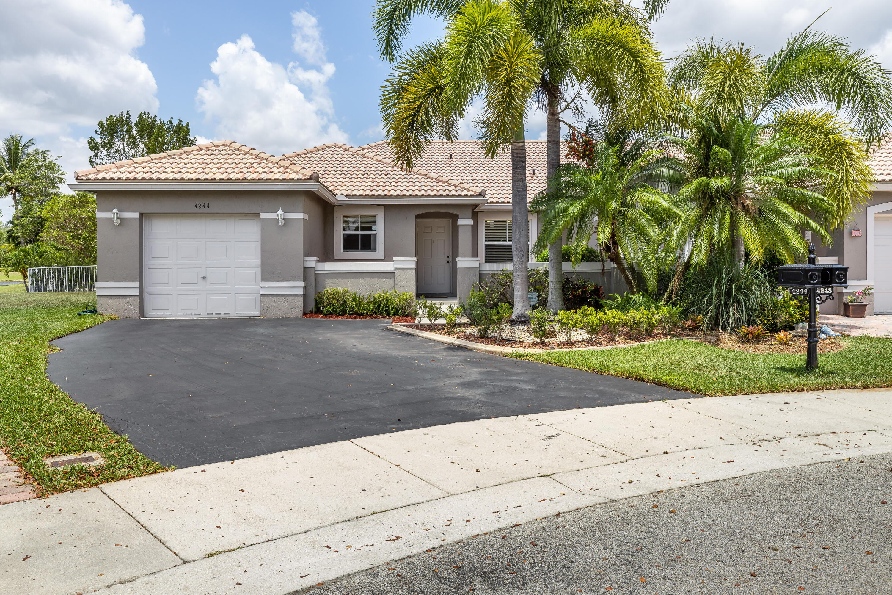 a front view of a house with a garden and palm trees