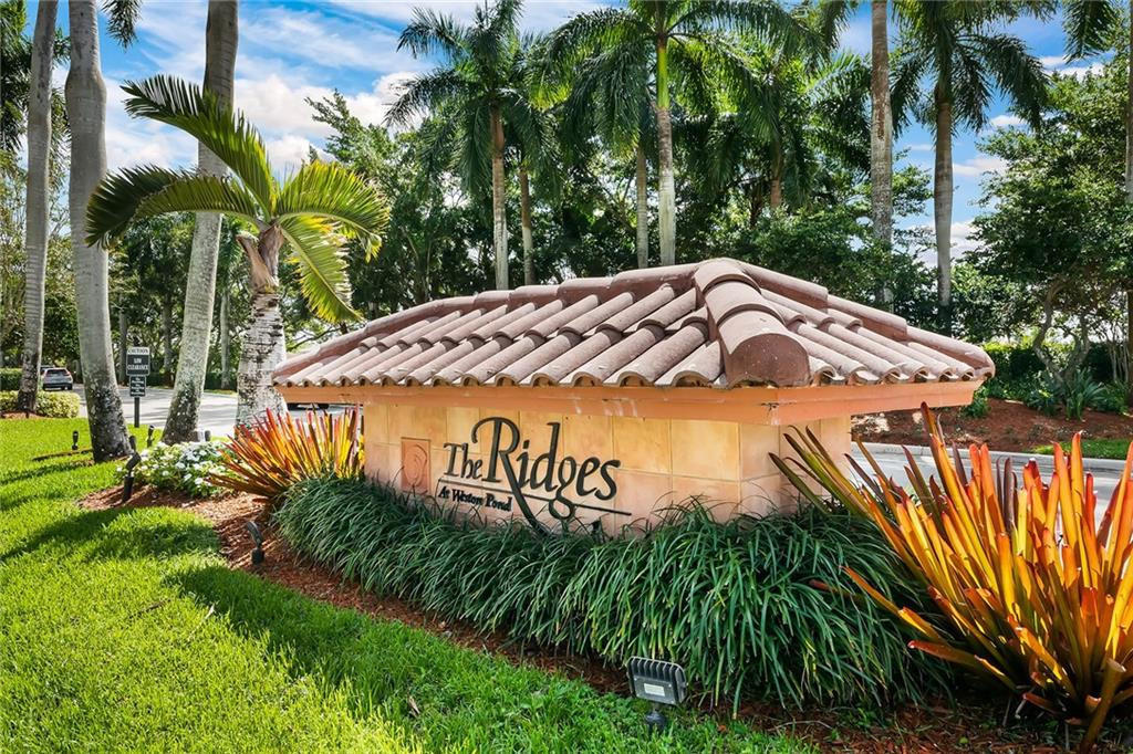 4244 Pine Ridge Court Weston, FL 33331 - Photo 27 of 34 a sign that is sitting on a brick wall with plants and large trees