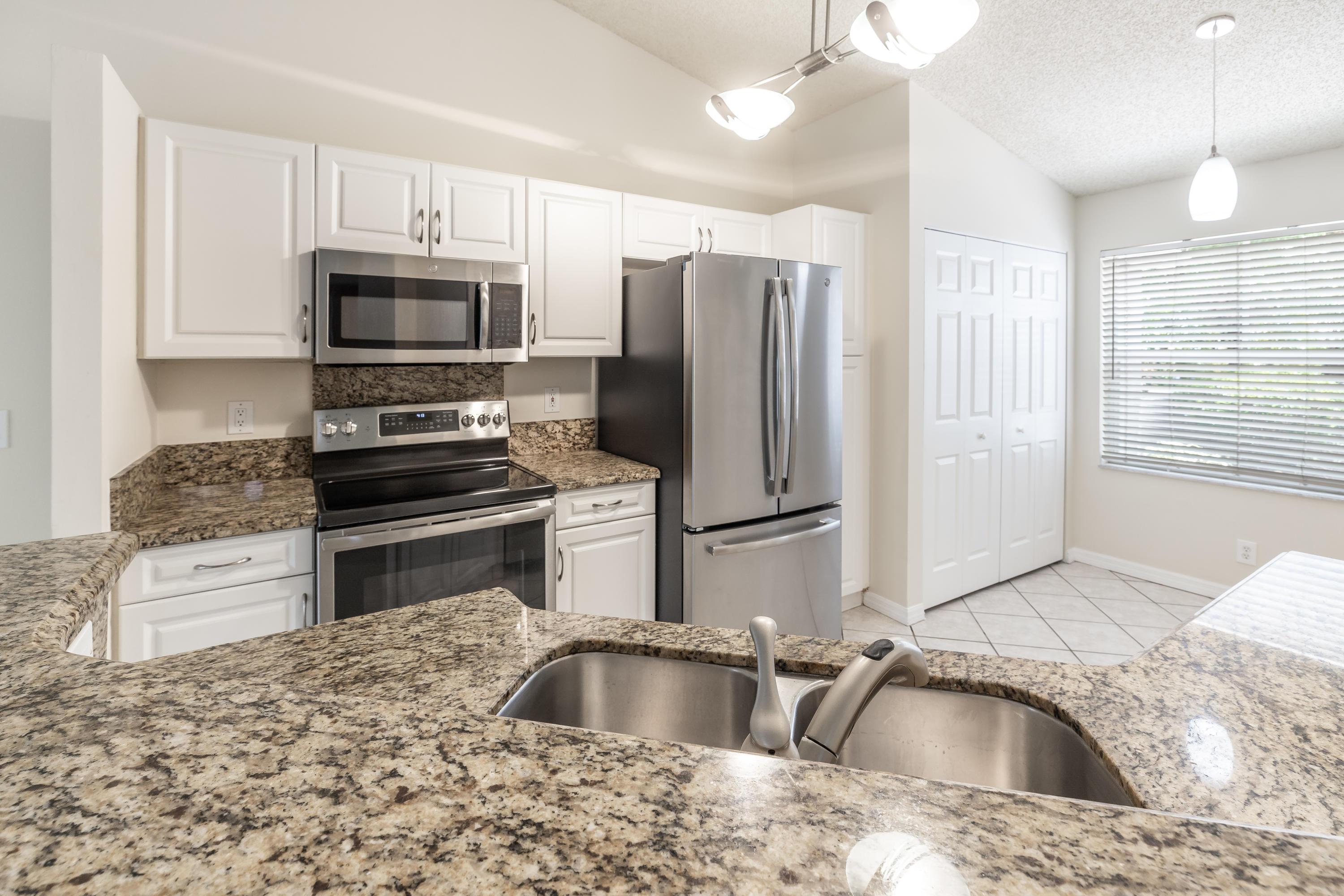 4244 Pine Ridge Court Weston, FL 33331 - Photo 8 of 34 a kitchen with stainless steel appliances granite countertop a sink refrigerator and microwave