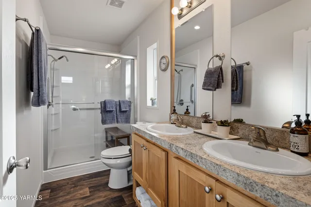 a bathroom with a granite countertop sink a toilet a mirror and shower