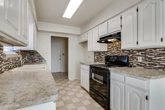 a kitchen with granite countertop a sink stove and cabinets