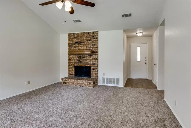 an empty room with windows and chandelier fan