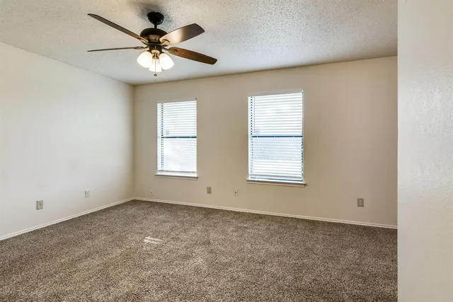 an empty room with windows and ceiling fan