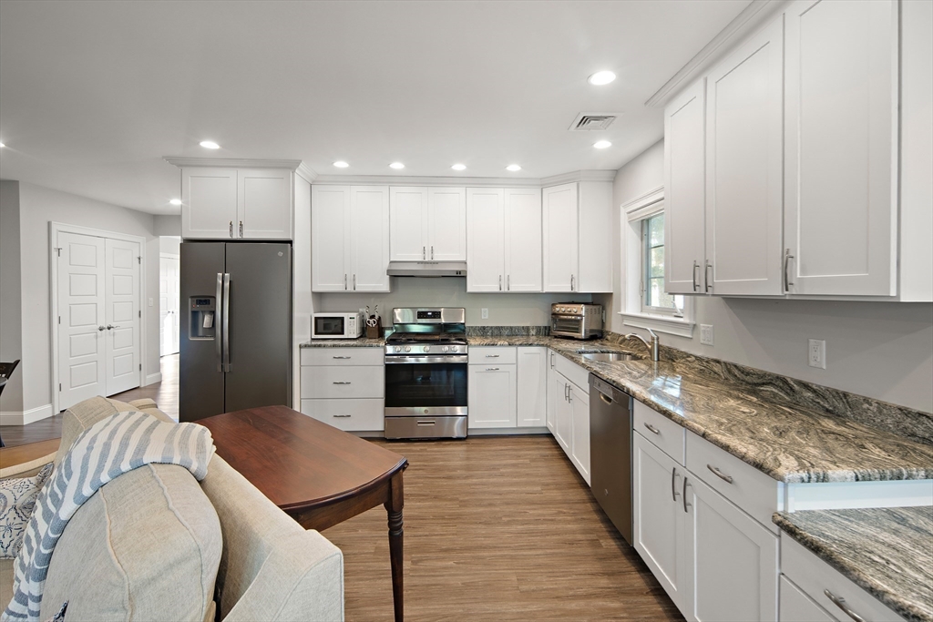 22 Peachtree Road Lexington, MA 02420 - Photo 33 of 42 a large kitchen with stainless steel appliances granite countertop a large stove top oven a refrigerator a sink and white cabinets with wooden floor