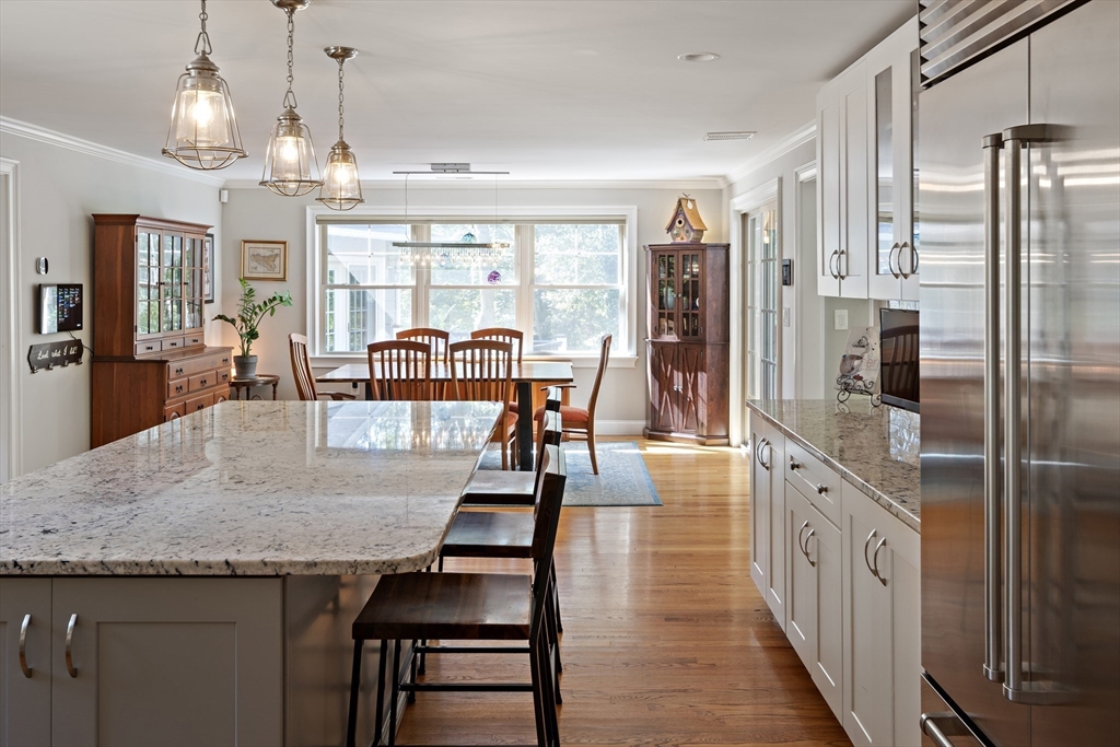 22 Peachtree Road Lexington, MA 02420 - Photo 6 of 42 a kitchen with stainless steel appliances granite countertop a kitchen island a refrigerator a stove a dining table and chairs with wooden floor