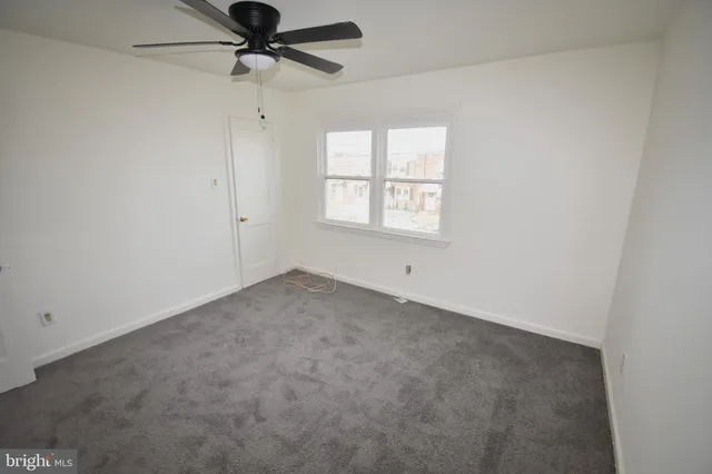an empty room with a window and a fan