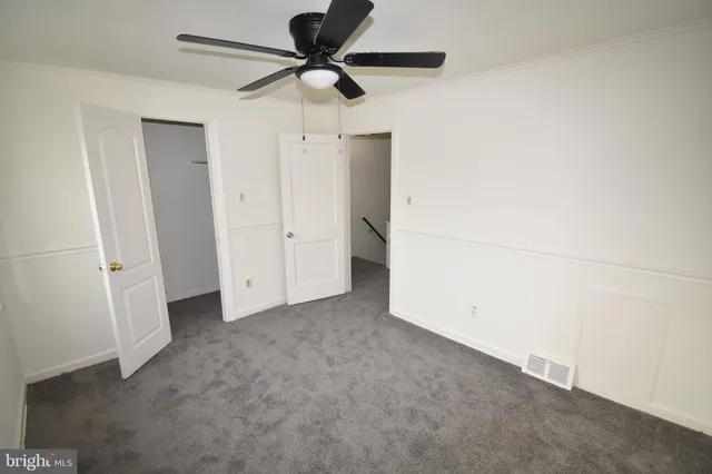 an empty room with windows and fan