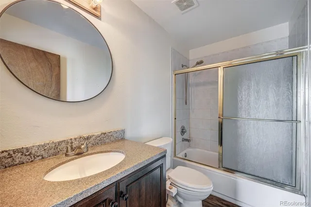 a bathroom with a granite countertop sink toilet and shower