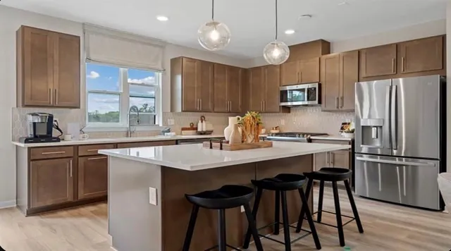 a kitchen with kitchen island granite countertop a table chairs microwave and refrigerator