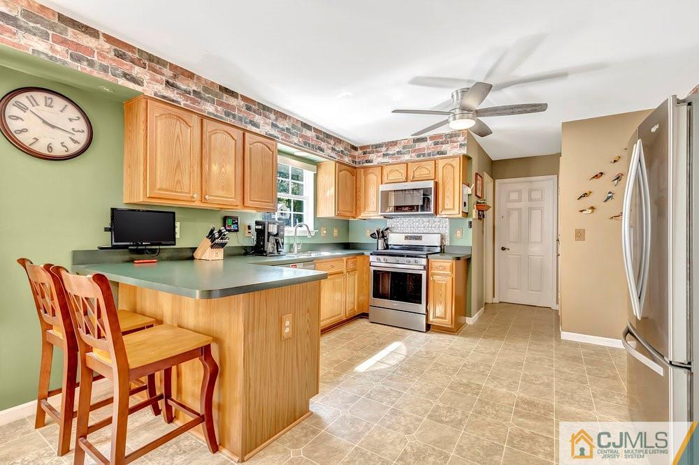 5 Netty Street Howell, NJ 07731 - Photo 13 of 36 a kitchen with stainless steel appliances granite countertop a stove top oven a refrigerator a oven with a dining table and chairs