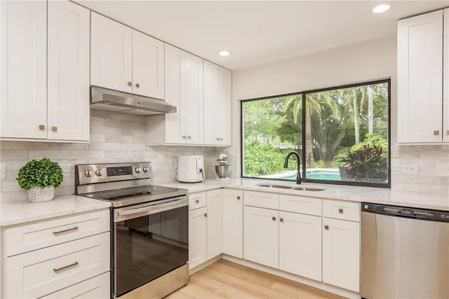 a kitchen with granite countertop white cabinets and a window