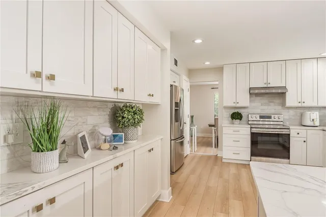 a kitchen with white cabinets and stainless steel appliances