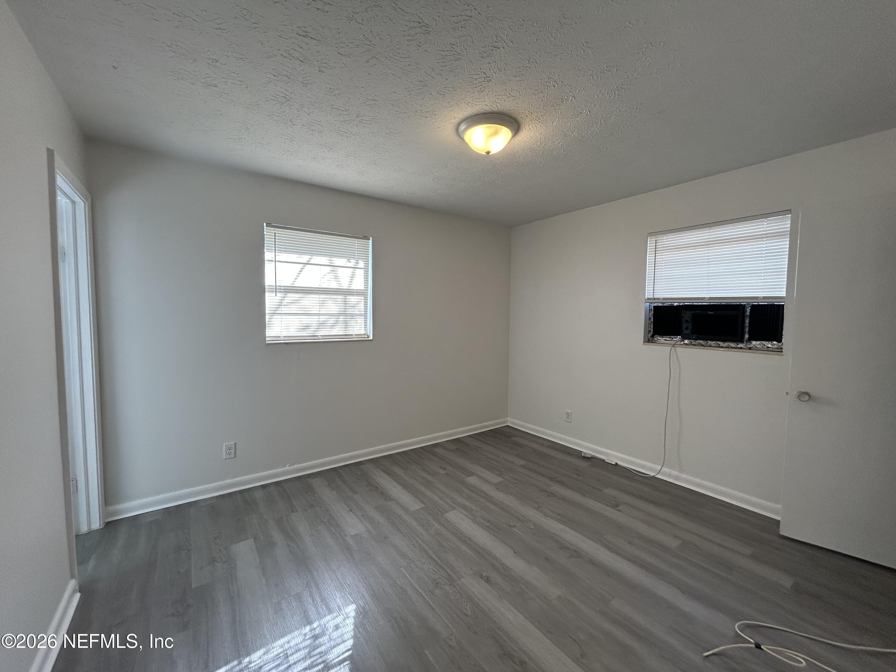 10610 Lone Star Road Jacksonville, FL 32225 - Photo 11 of 18 an empty room with wooden floor and windows