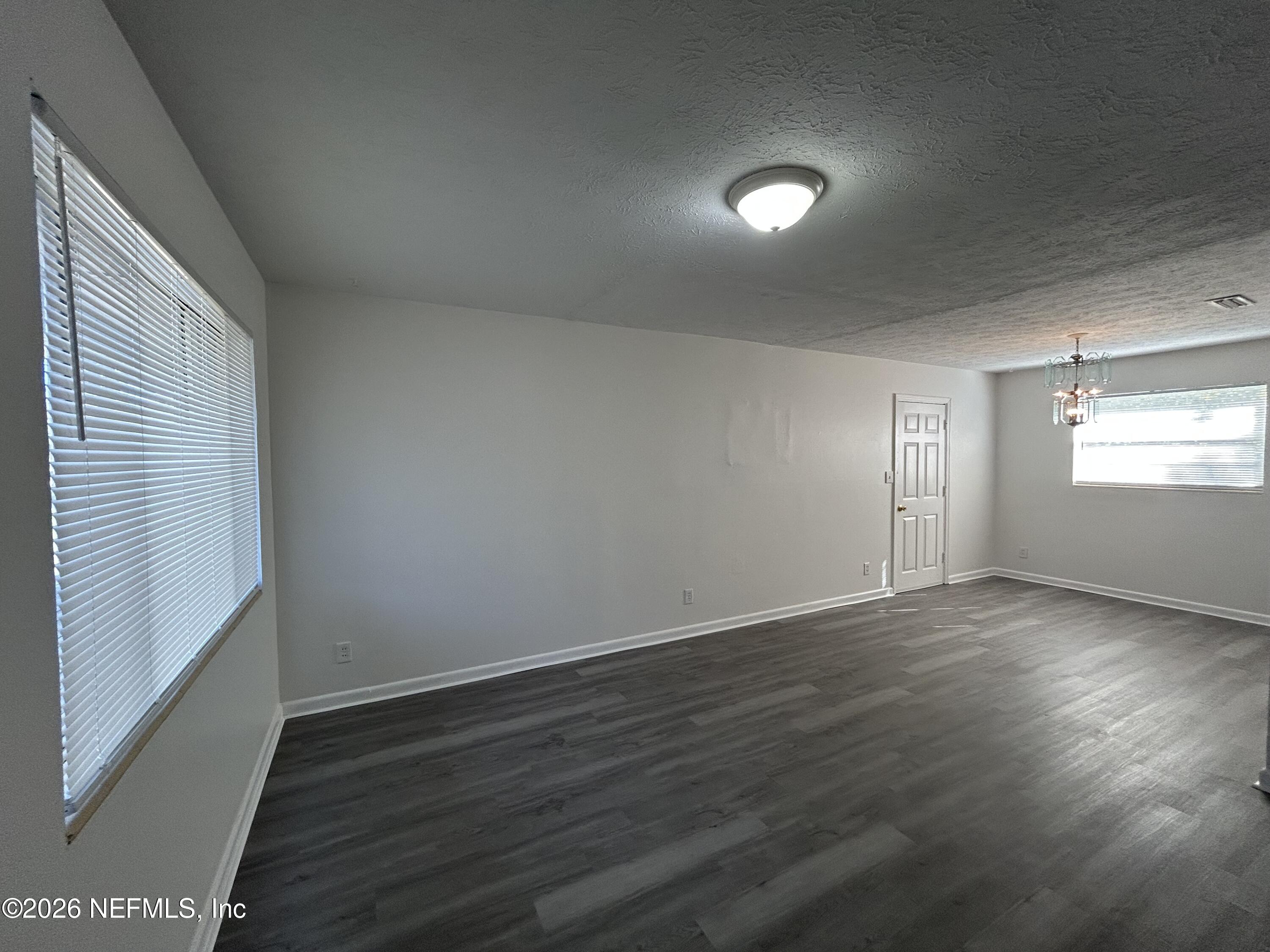 10610 Lone Star Road Jacksonville, FL 32225 - Photo 7 of 18 an empty room with wooden floor and windows