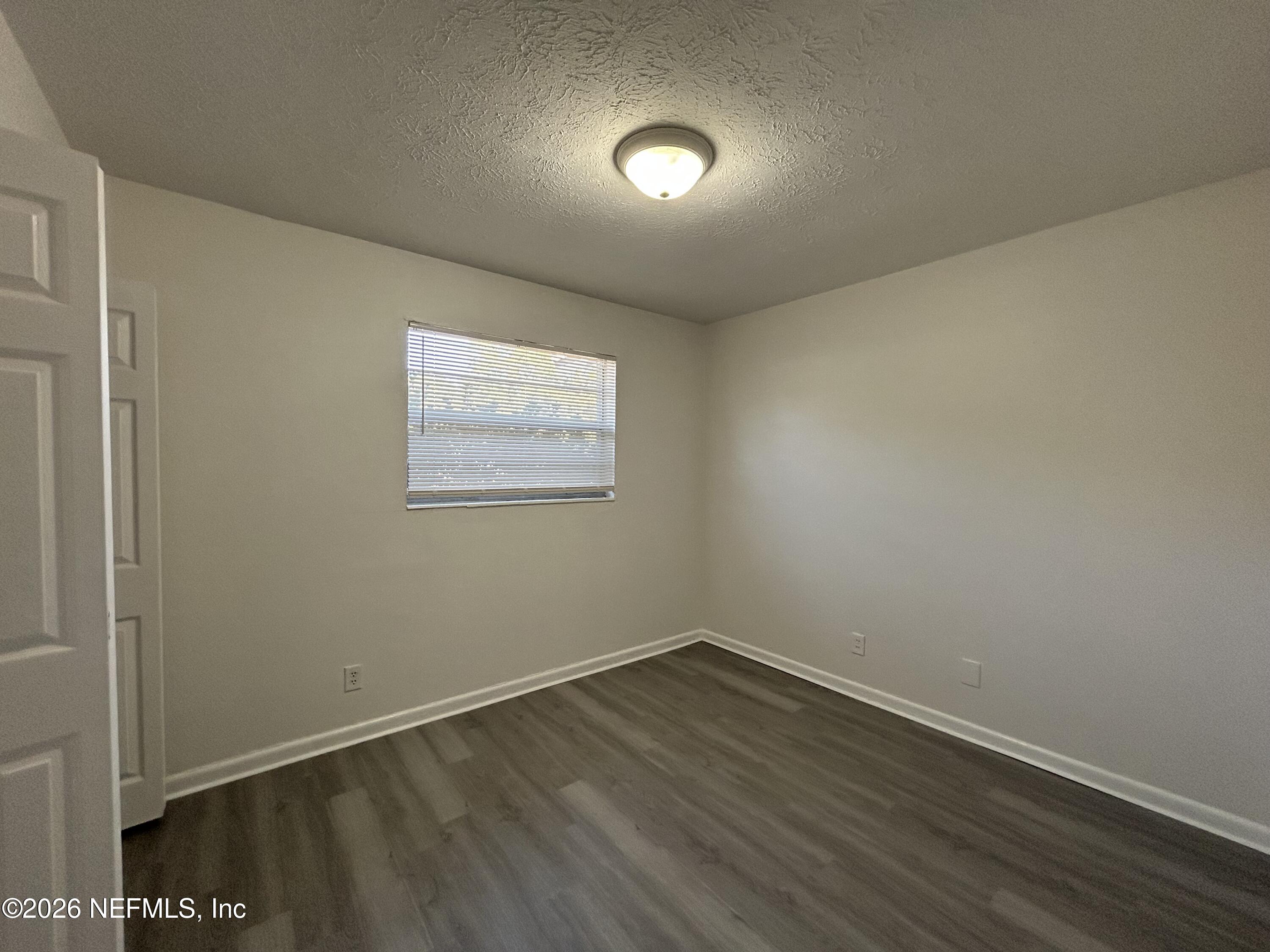10610 Lone Star Road Jacksonville, FL 32225 - Photo 8 of 18 an empty room with wooden floor and windows