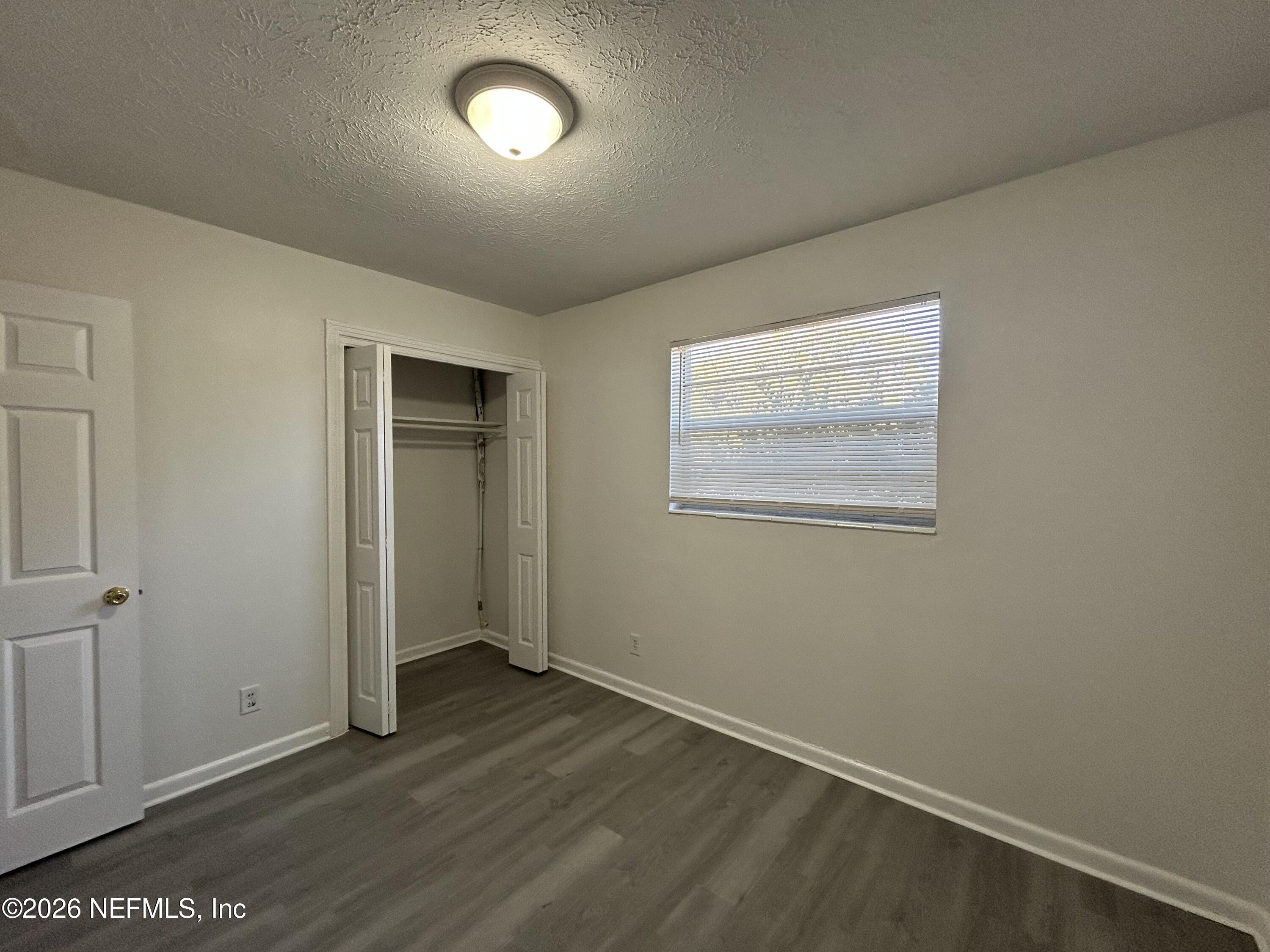 10610 Lone Star Road Jacksonville, FL 32225 - Photo 9 of 18 an empty room with wooden floor and windows