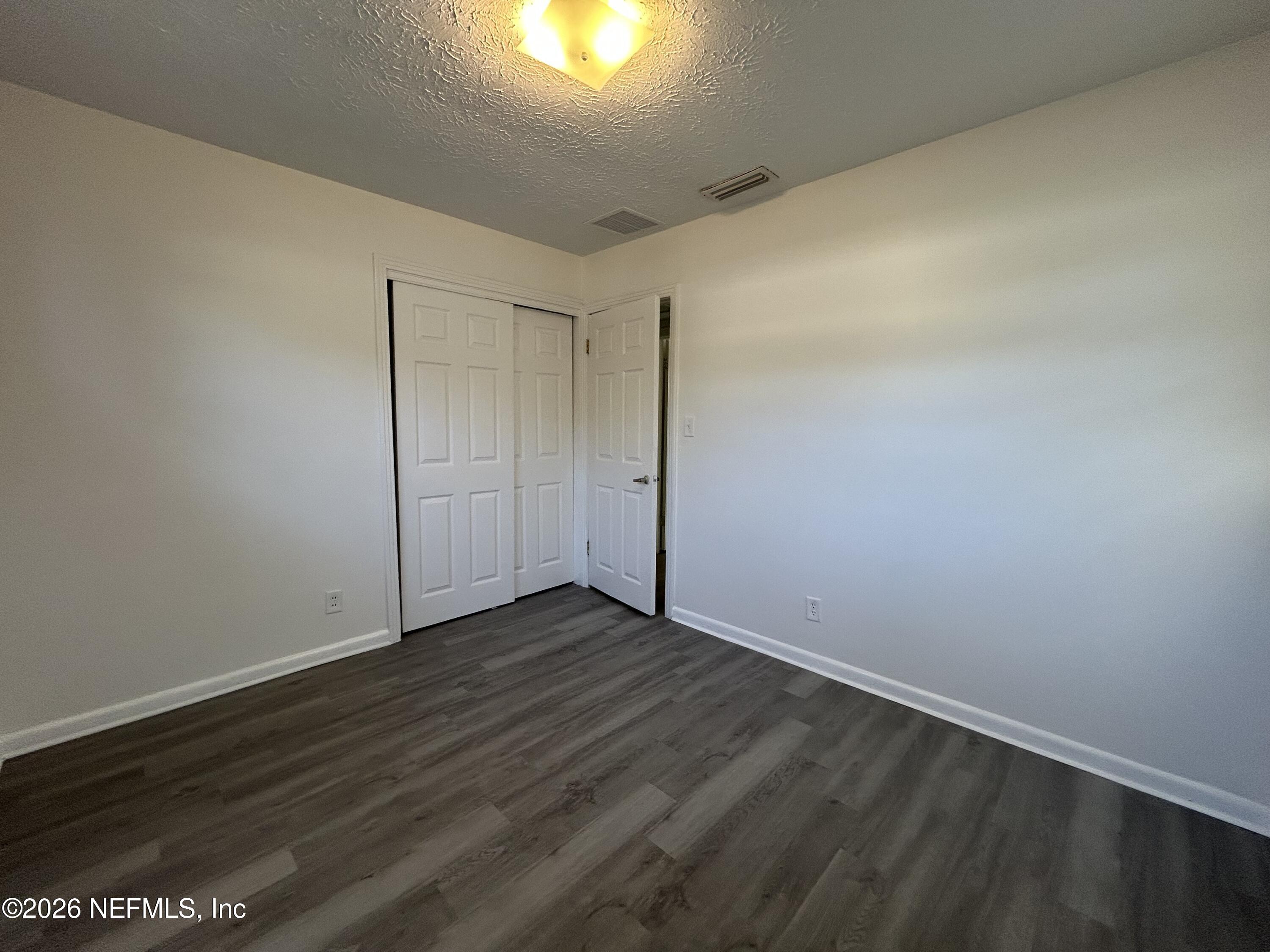 10610 Lone Star Road Jacksonville, FL 32225 - Photo 10 of 18 an empty room with wooden floor and windows with curtains