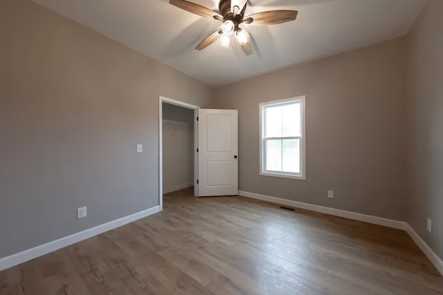 a view of an empty room with wooden floor and a window