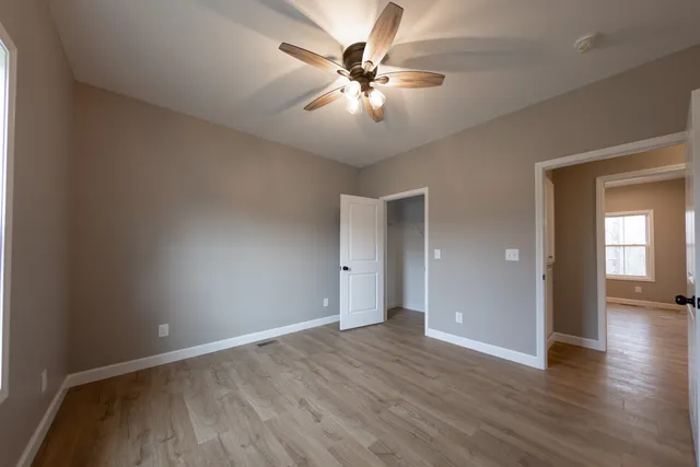 an empty room with wooden floor and a ceiling fan