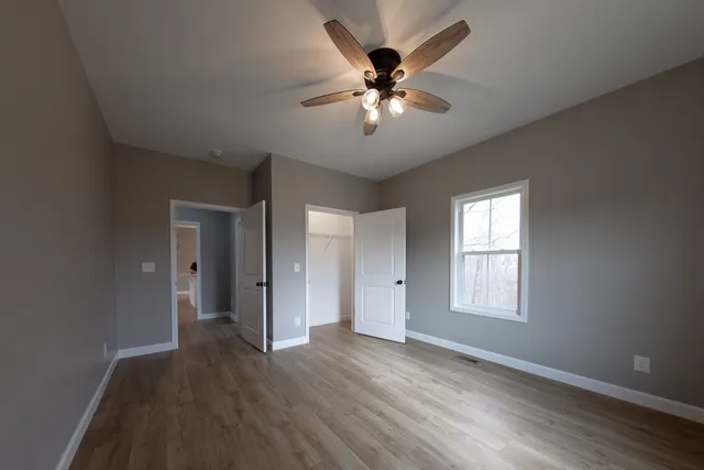 a view of empty room with wooden floor and fan