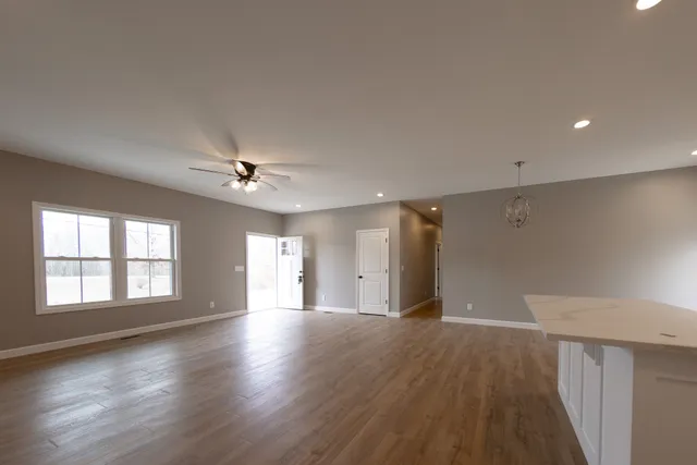 a view of an empty room with window and wooden floor