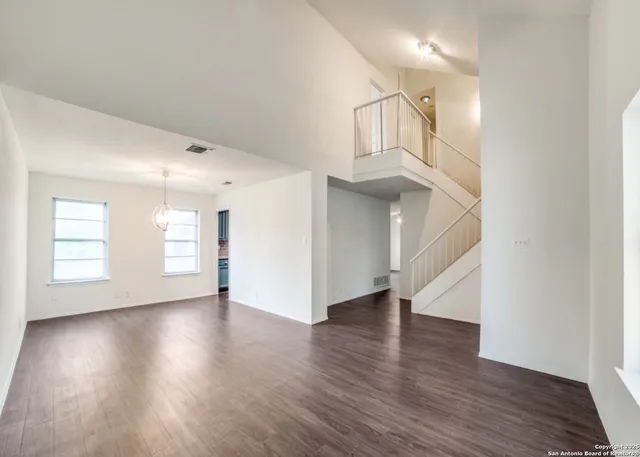 an empty room with wooden floor and staircase