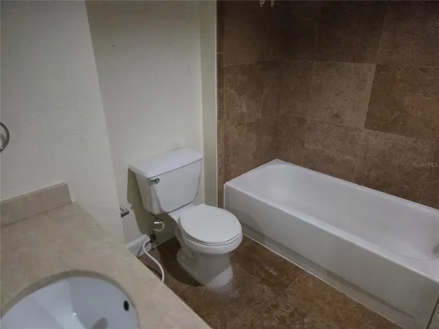 a white toilet sitting next to a bath tub