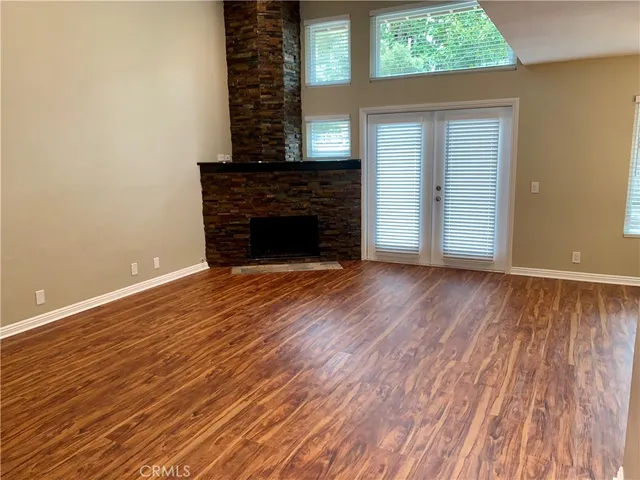 an empty room with wooden floor a fireplace and windows