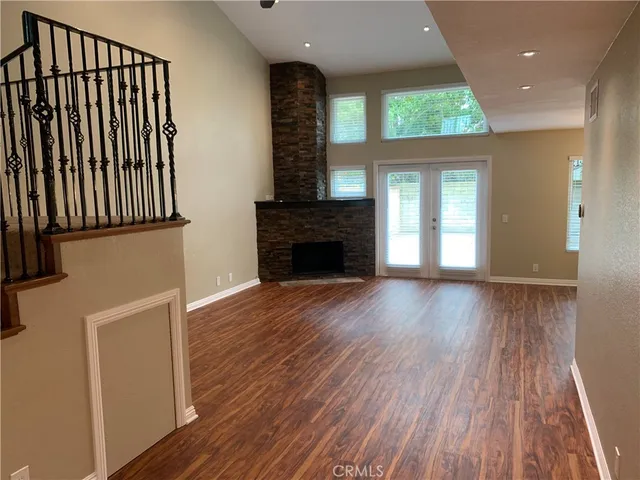 an empty room with wooden floor a fireplace and windows
