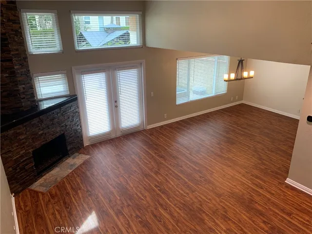 an empty room with wooden floor fireplace and windows