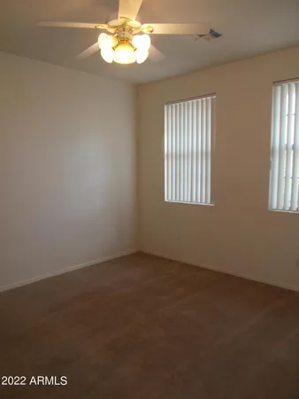 an empty room with windows and chandelier fan